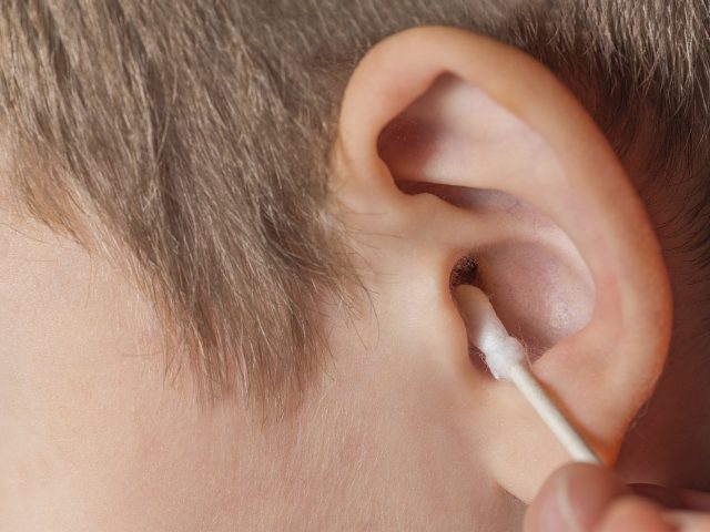 Cleaning the ear with a cotton swab.