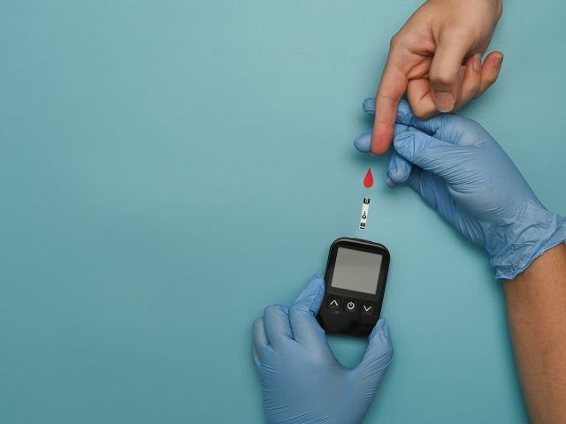 Overhead view of doctor check up blood glucose levels of diabetic woman. Diabetes and health care concept