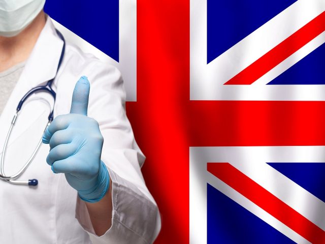 Uk Doctor's Hand Showing Thumb Up Positive Gesture On Flag Of Un