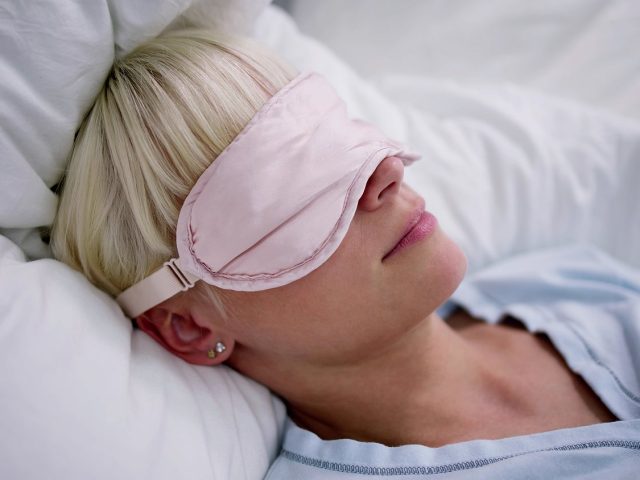Young Woman Sleeping With Sleep Mask In Bedroom